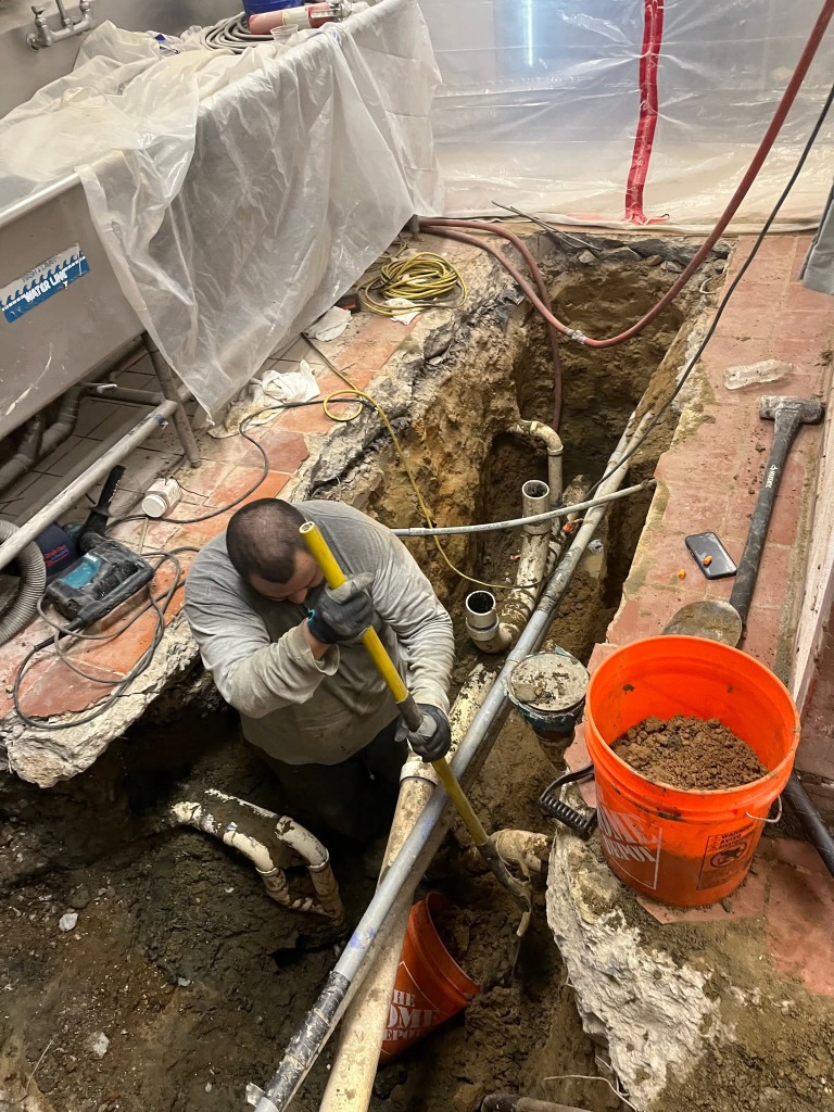 Plumber trenching indoor slab for commercial pipe repair